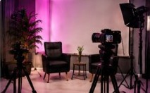 Set de entrevistas con sillones, luces magenta y cámaras en trípode