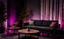 Sala lounge con sofá oscuro, mesas de madera y luz magenta