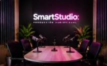 Mesa de podcast con micrófonos y el logo de Smart Studio en una pantalla